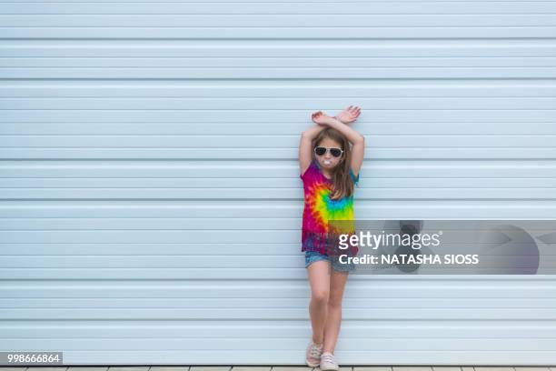 young girl wearing a tie dye shirt posing in front of a garage wall - tie dye stock pictures, royalty-free photos & images