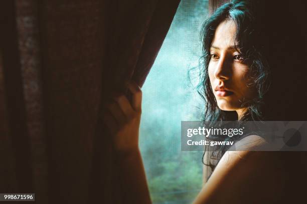 beautiful serene young woman thinks near window. - gawrav stock pictures, royalty-free photos & images