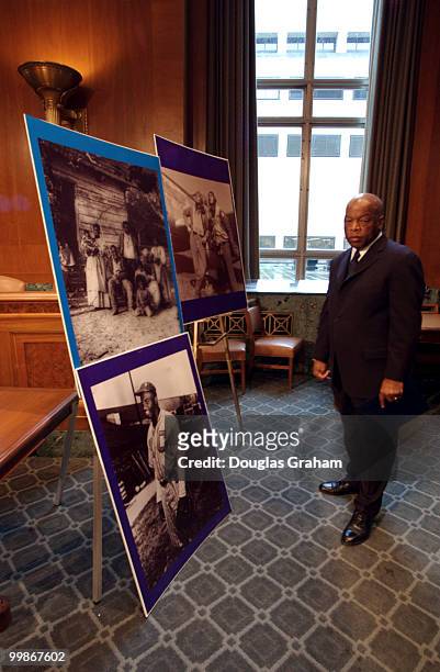 John Lewis, D-GA., looks at photos of early African Americans before the start of a news conference to unveil legislation authorizing the c of...