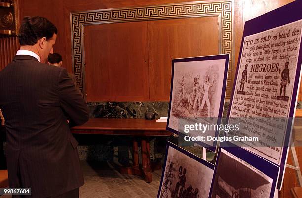 Rick Santorum, R-Pa., looks at photos of early African Americans before the start of a news conference to unveil legislation authorizing the c of...