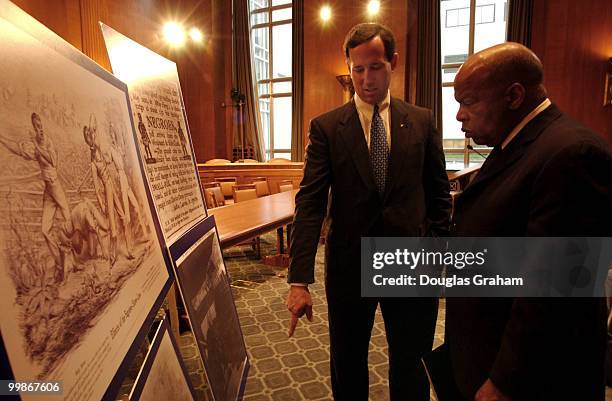 Rick Santorum, R-Pa., and John Lewis, D-GA., look at photos of early African Americans before the start of a news conference to unveil legislation...