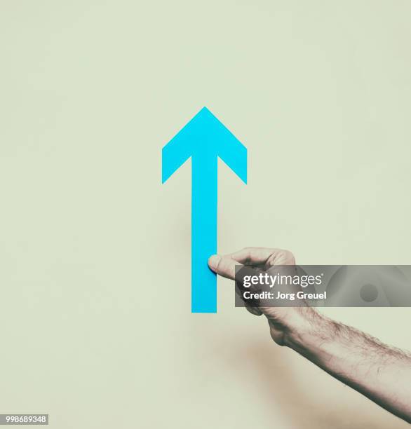 hand holding paper arrow - jorg greuel stock pictures, royalty-free photos & images