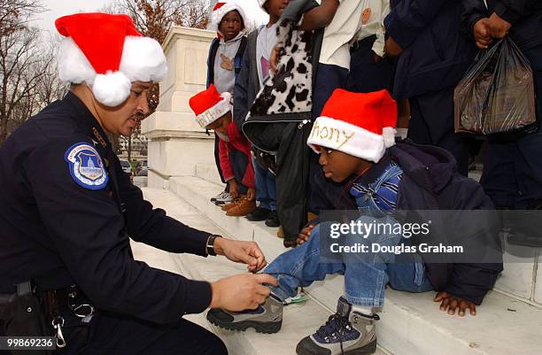 Capitol Police Office, G.S. Jackson ties Anthony Mease's shoe lace during the Second Annual Birney Elementary Christmas Party sponsored by the United...