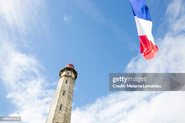 view from the ground of the 1854 grand phare des baleines lighthouse with a french flag floating... - phare stock-fotos und bilder