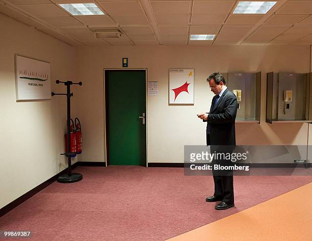 George Papaconstantinou, Greece's finance minister, examines his mobile phone before giving a news conference following the meeting of European Union...