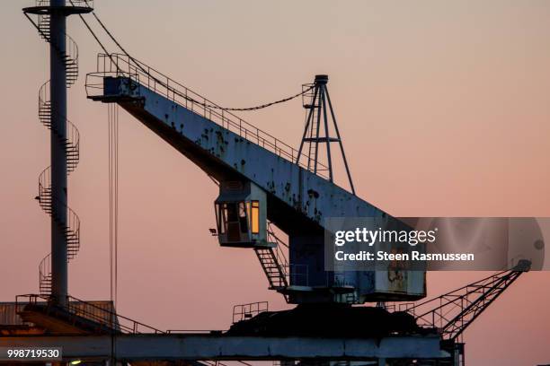 the old crane in the colorful sunset - steen stock-fotos und bilder