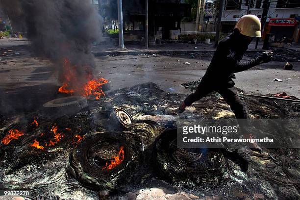 An anti-government red shirt protester runs across burning tires on May 18, 2010 in Bangkok, Thailand. Protesters have clashed with military forces...