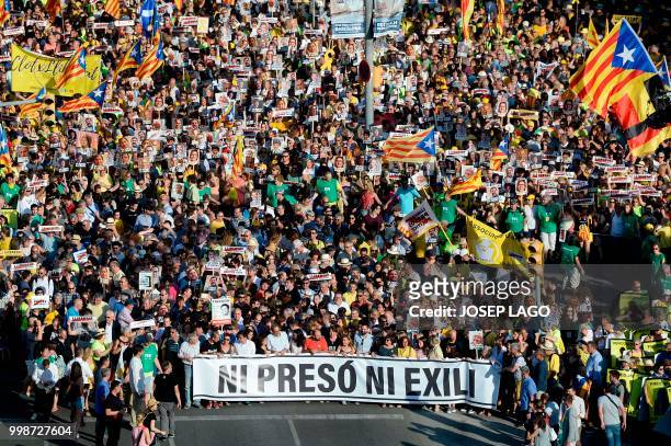 People holding a banner reading "No jail, No exile" attend a demonstration on July 14, 2018 in Barcelona, calling for the release of separatist...