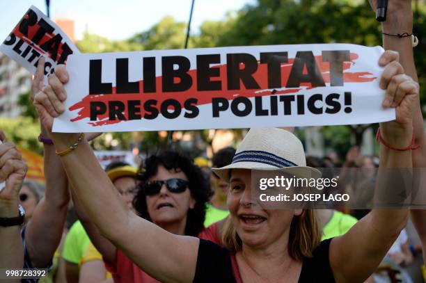 Woman holds a placard reading "Free political prisoners" during a demonstration on July 14, 2018 in Barcelona, calling for the release of separatist...