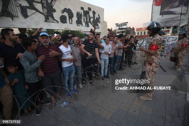 Members of the Iraqi security forces stand guard as protesters in the capital Baghdad's Tahrir Square demonstrate against unemployment on July 14,...