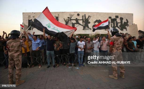 Members of the Iraqi security forces stand guard as protesters in the capital Baghdad's Tahrir Square demonstrate against unemployment on July 14,...