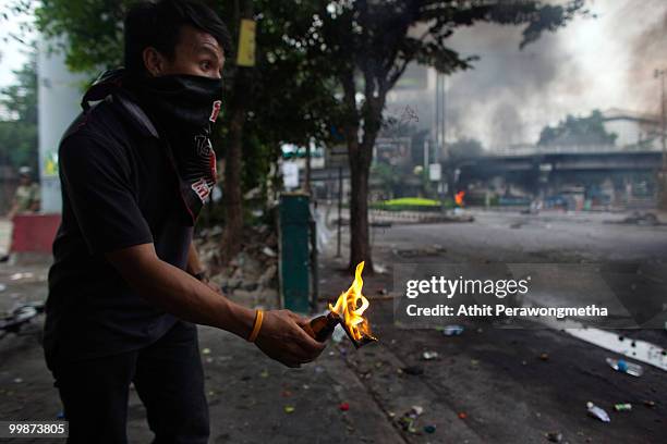 An anti-government red shirt protester prepares to throw a molotov cocktail on May 18, 2010 in Bangkok, Thailand. Protesters have clashed with...