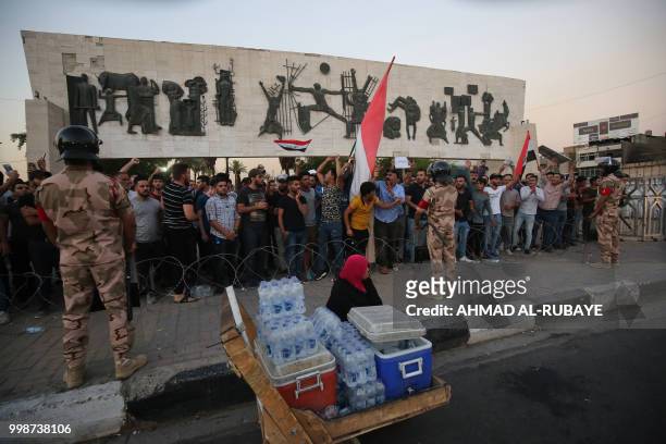 Members of the Iraqi security forces stand guard as protesters in the capital Baghdad's Tahrir Square demonstrate against unemployment on July 14,...