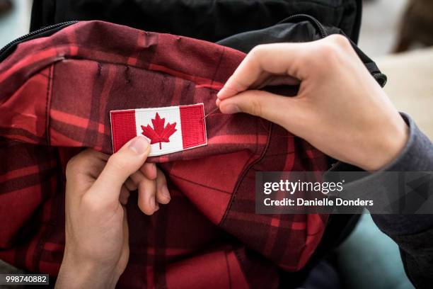 sewing a canadian flag onto a backpack for international travel - danielle donders stock pictures, royalty-free photos & images