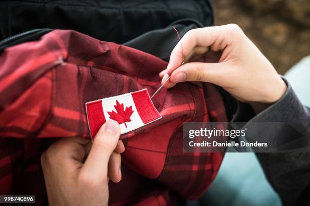 sewing a canadian flag onto a backpack for international travel - canadian culture stock pictures, royalty-free photos & images