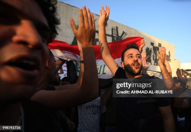 Iraqi protesters carry the national flag as they demonstrate in the capital Baghdad's Tahrir Square against unemployment on July 14, 2018. - Two...