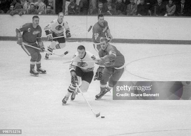 Phil Esposito of the Chicago Blackhawks skates on the ice with the puck as Doug Harvey of the Detroit Red Wings defends during an NHL game circa 1967...