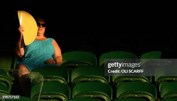 Spectator uses a fan to as she sits on Centre Court to watch South Africa's Raven Klaasen and New Zealand's Michael Venus play against US player Mike...