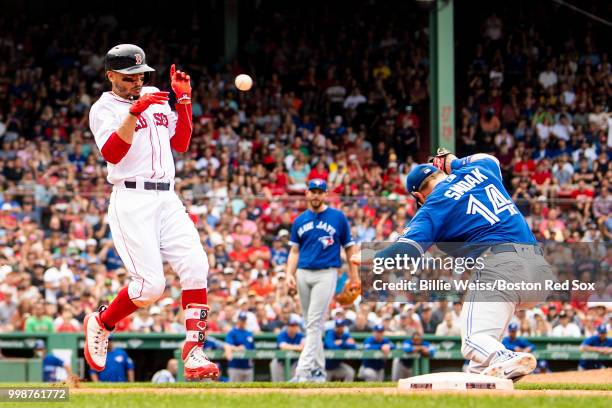 Mookie Betts of the Boston Red Sox advances on an overthrown ball to Justin Smoak of the Toronto Blue Jays during the eighth inning of a game on July...