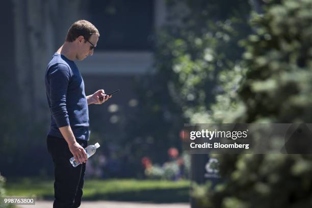 Mark Zuckerberg, chief executive officer and founder of Facebook Inc., looks at his phone after the morning session at the Allen & Co. Media and...