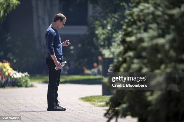 Mark Zuckerberg, chief executive officer and founder of Facebook Inc., looks at his phone after the morning session at the Allen & Co. Media and...