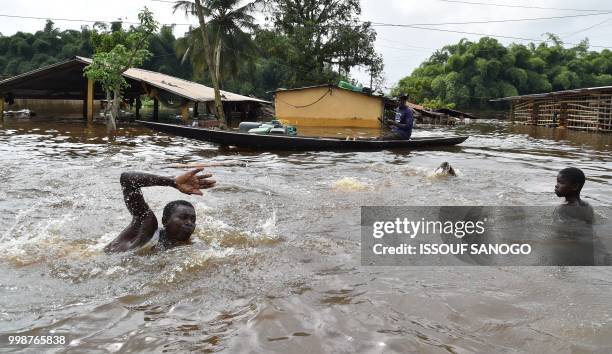 This picture taken on July 14, 2018 shows a man swimming in a flooded area in Aboisso, 120 kms from Abidjan after a heavy rainfall.