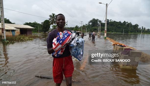 This picture taken on July 14, 2018 shows people walking in a flooded area in Aboisso, 120 kms from Abidjan after a heavy rainfall.