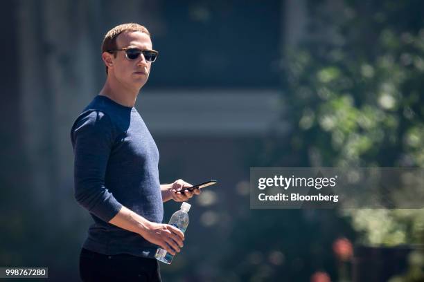 Mark Zuckerberg, chief executive officer and founder of Facebook Inc., holds his phone after the morning session at the Allen & Co. Media and...