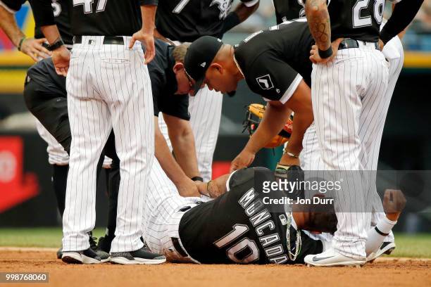 Yoan Moncada of the Chicago White Sox is treated by head trainer Herm Schneider after a right knee injury after colliding with Paulo Orlando of the...