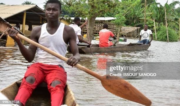 This picture taken on July 14, 2018 shows men in a pirogue in a flooded area in Aboisso, 120 kms from Abidjan after a heavy rainfall.