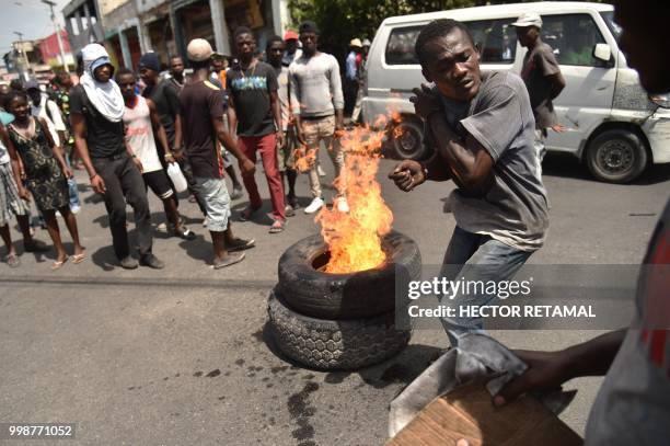 Demonstrator avoids getting burned after he set fire to tires during a march through the streets of Port-au-Prince, on July 14, 2018 to protest...