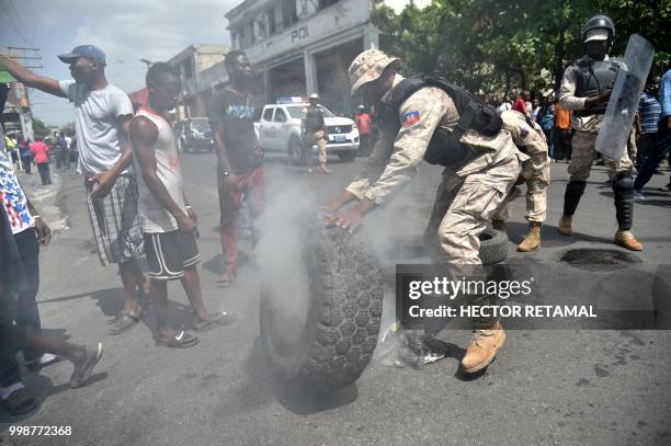 Haitian Police put out fire from the burning tires put down by demonstrators during a march through the streets of Port-au-Prince, on July 14, 2018...