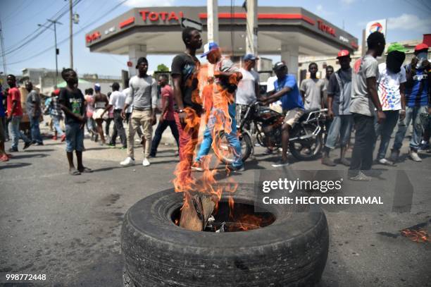 Demonstrators set fire to tires during a march through the streets of Port-au-Prince, on July 14, 2018 to protest against the government of President...