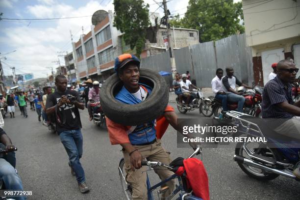 Demonstrator carries a tire during a march through the streets of Port-au-Prince, on July 14, 2018 to protest against the government of President...