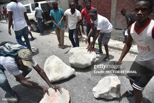 Demonstrators use boulders to make a barricade during a march through the streets of Port-au-Prince, on July 14, 2018 to protest against the...