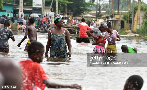 This picture taken on July 14, 2018 shows people walking in a flooded area in Aboisso, 120 kms from Abidjan after a heavy rainfall.