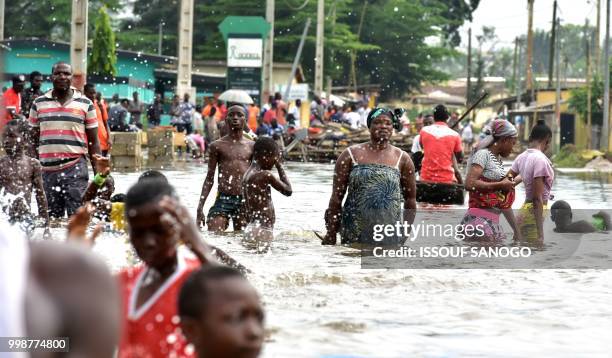 This picture taken on July 14, 2018 shows people walking in a flooded area in Aboisso, 120 kms from Abidjan after a heavy rainfall.