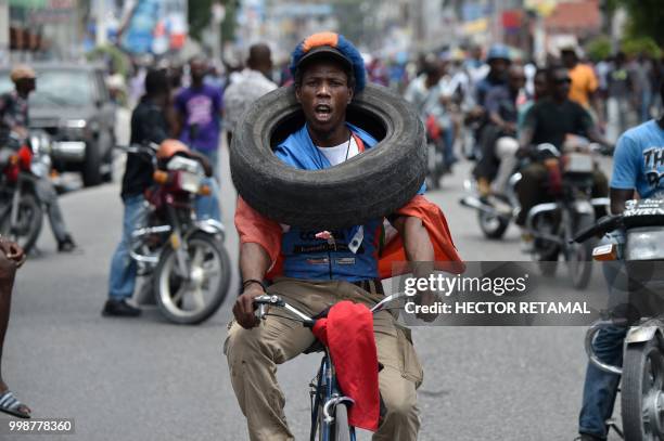 Demonstrator carries a tire during a march through the streets of Port-au-Prince, on July 14, 2018 to protest against the government of President...