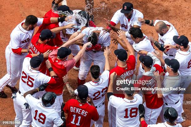 Xander Bogaerts of the Boston Red Sox is mobbed by teammates after hitting a walk-off grand slam home run during the tenth inning of a game against...