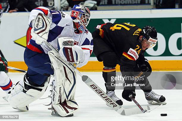 Goaltender Peter Budaj of Slovakia is challenged by Andre Rankel of Germany during the IIHF World Championship qualification round match between...