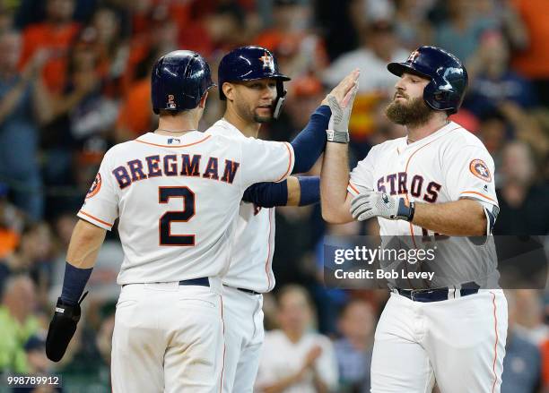 Tyler White of the Houston Astros receives a high five from Alex Bregman and Yuli Gurriel after hitting home run in the seventh inning against the...