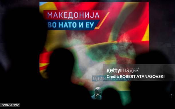 People celebrate the invitation to join NATO at an event in Skopje on July 14 in front of video screen where we can read "Macedonia in EU and Nato"...