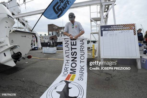 With the tournament over on Saturday, Harry Papp rolls of the tournament banner on Pier three at the 32nd Annual North Atlantic Monster Shark Fishing...