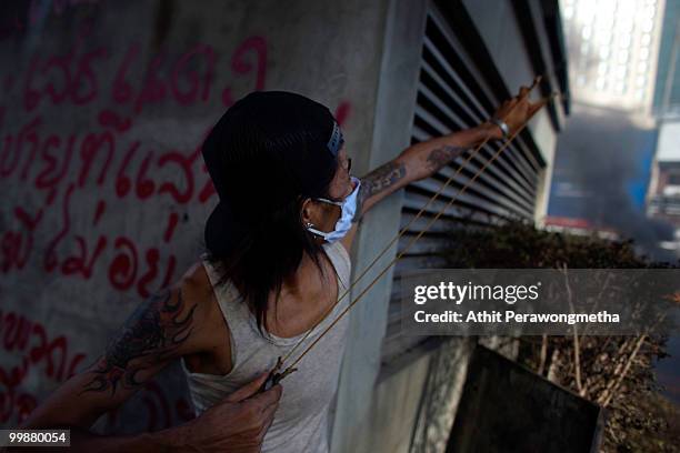 An anti-government red shirt protester fires a slingshot towards Thai security forces on May 18, 2010 in Bangkok, Thailand. Protesters have clashed...