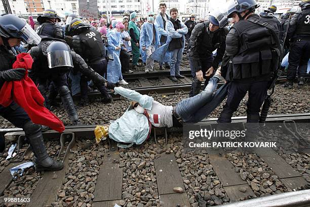 French policemen evacuate a person during a demonstration of French anaesthetist nurses as they stand on tracks near the Montparnasse train station...