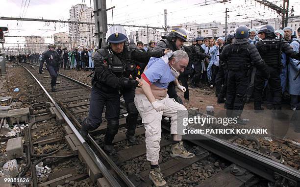 French policemen evacuate a man during a demonstration of French anaesthetist nurses as they stand on tracks near the Montparnasse train station on...