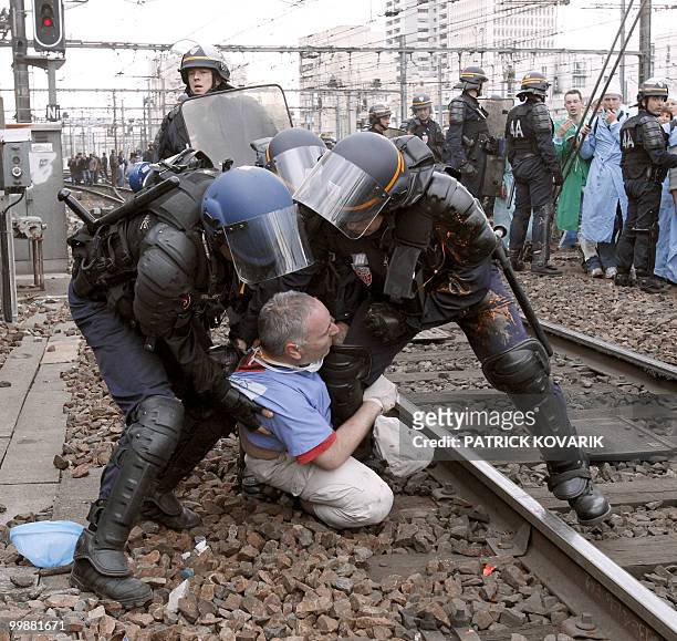 French policemen evacuate a man during a demonstration of French anaesthetist nurses as they stand on tracks near the Montparnasse train station on...