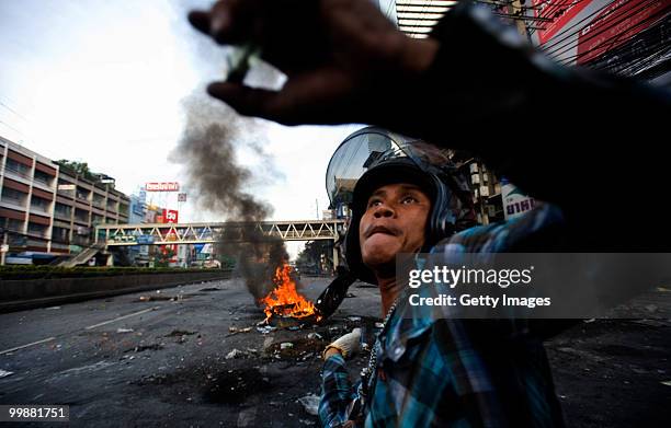 Thai anti-government red shirt protester hurls a large firecracker over a barricade during clashes on May 18, 2010 in Bangkok, Thailand. Protesters...