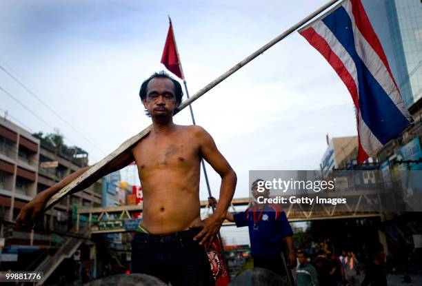 Thai anti-government red shirt protester lets out a sigh as he watches people move tyres to extend their barricade on May 18, 2010 in Bangkok,...