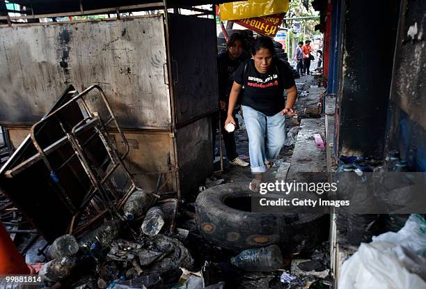 Thai woman walks down a sidewalk littered with the debris from shops looted by anti-government red shirt protesters on May 18, 2010 in Bangkok,...